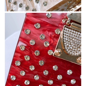 Macro detail of red acrylic marble texture and luxury crystal studs on evening clutch