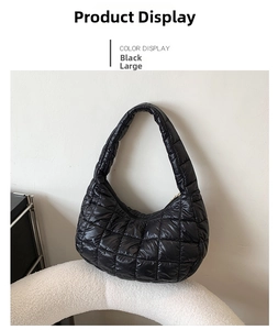 Detail of a large black quilted hobo shoulder bag displayed on a white podium