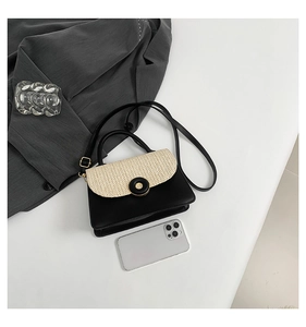 Detail of crossbody bag featuring woven straw flap and round black hardware buckle