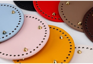 Detail of round PU leather bag base with gold metal feet and pre-punched holes for DIY