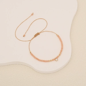 Handmade bohemian braided bracelet with peach beads and sparkling round zircon pendant