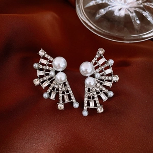 Detailed macro view of vintage silver flower earrings with pearls on red satin fabric