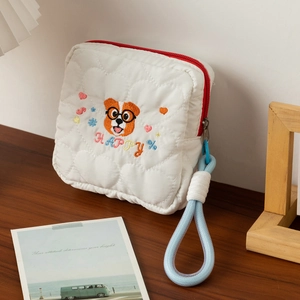 Vue détaillée de la trousse de toilette matelassée avec broderie chien sur bois.