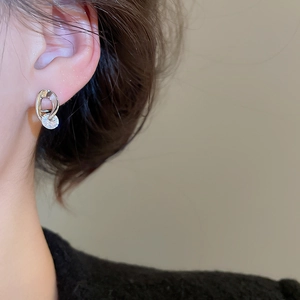 Detail view of silver interlocking earrings featuring a sparkling round zircon stone
