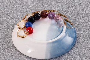 Macro shot of 10mm faceted crystal glass hook earrings in multiple colors on ceramic edge