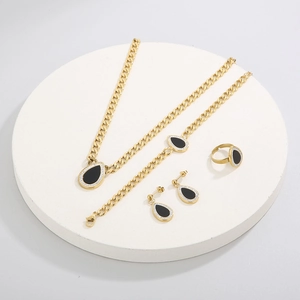 Detail of four-piece gold teardrop set with black onyx and pavé diamonds on a white pedestal