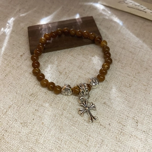 Gros plan d'un bracelet en perles de pierre avec croix argentée vintage et entretoises