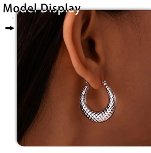 Macro shot of silver U-shaped earrings with diamond pattern on a model's ear
