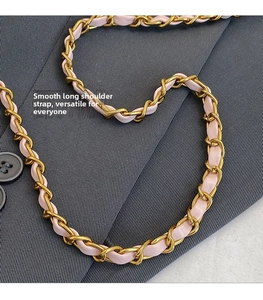 Detail of pink leather woven gold chain strap on a dark grey wool blazer