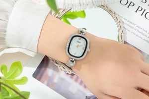 Elegant oval quartz watch with crystal bezel and silver mesh strap on woman's wrist