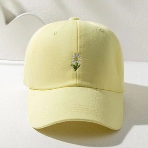 Close-up of yellow baseball cap featuring delicate daisy embroidery and canvas texture