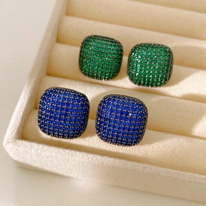 Detailed macro view of vintage square pave stud earrings in emerald green and sapphire blue