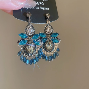 Close-up of vintage flower drop earrings with blue crystals and ornate silver settings