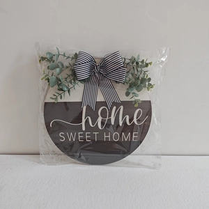Detail of wooden home sweet home sign with striped bow and green eucalyptus leaves
