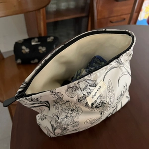 Detail of floral jacquard makeup bag with simple wish label and top zipper closure