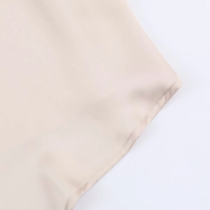 Detailed macro shot of the smooth champagne satin fabric hem with precise stitching