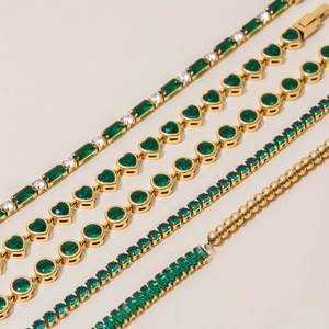 Detailed close-up of gold bracelets with emerald and clear zircon heart-shaped charms