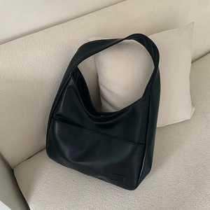 Detail einer großen schwarzen minimalistischen PU-Leder-Einkaufstasche auf dem Sofa