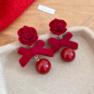 Gros plan de boucles d'oreilles fleurs et nœuds floqués rouges avec perle brillante