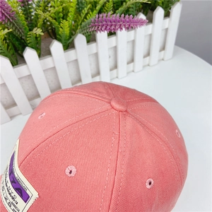 Close-up of pink cotton baseball cap crown featuring retro patch and detailed stitching