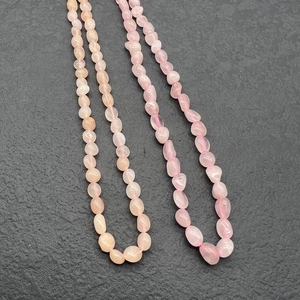 Macro detail of irregular pink rose quartz gemstone beads on stainless steel necklace