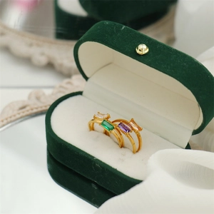 Three 18K gold-plated square stone rings in white, green, and purple on green velvet