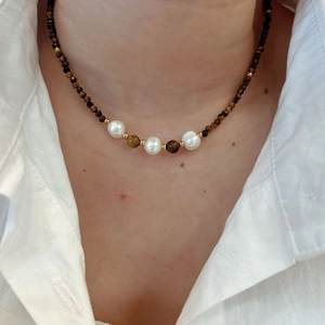 Water drop tiger eye stone necklace with white pearls on a model wearing a white shirt