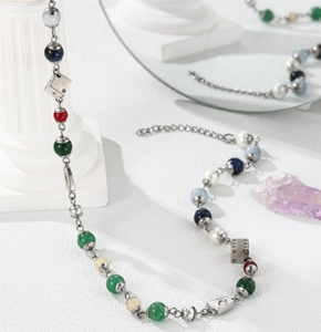 Detail of beaded necklace with colorful dice and silver heart charms on a Roman column