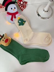 Detail of Christmas cotton socks with 3D plush reindeer and tree motifs on white background
