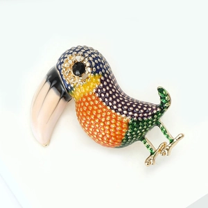 Macro view of vintage enamel toucan brooch with vibrant colors and gold dot texture