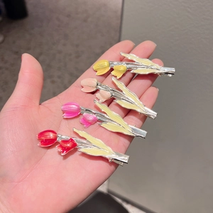 Detail showing four colorful tulip hair clips in yellow, pink, and red enamel finish