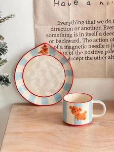 Detail view of blue striped ceramic mug and plate set with 3D puppy relief on wood table