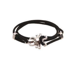 Detail of black woven cord bracelet featuring a polished silver octopus charm on white background
