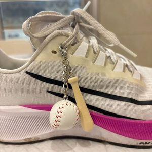 Detailed view of mini baseball bat and ball keychain attached to a white sneaker