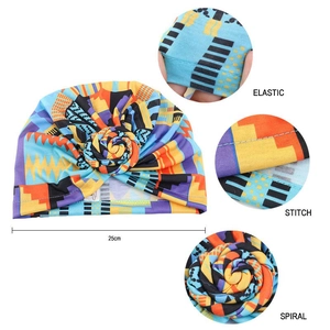 Detail view of ethnic turban hat showing 25cm width, elastic fabric and spiral flower