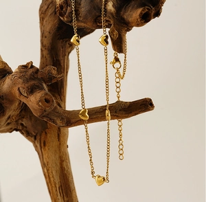 Detailansicht der goldenen Herz-Halskette, elegant über einen natürlichen Ast drapiert