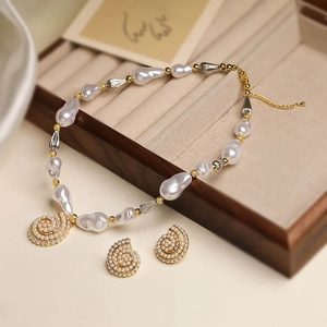 Detailed macro of baroque pearl jewelry set with golden shell charms on wooden display box