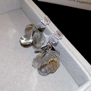 Macro shot of silver petal earrings with trapezoid zircon stones on a gray jewelry box