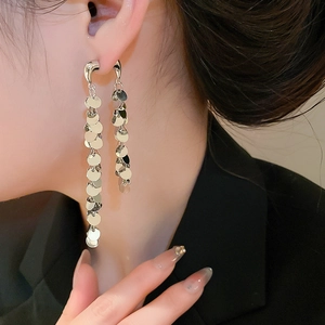 Vue latérale macro de boucles d'oreilles pampilles argentées avec sequins en métal