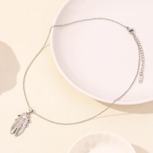 Close-up of silver cicada pendant and O-chain showing the S.STEEL material engraving