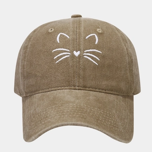 Close-up of white cat face embroidery on vintage washed cotton baseball cap texture