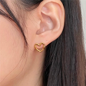 Close-up of golden hollow heart earrings with organic fluid design worn on ear