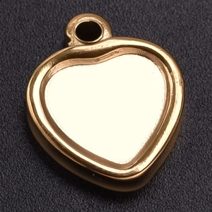 Macro shot of polished gold heart pendant showing smooth metal surface and top ring