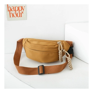 Detail of yellow canvas kids chest bag with woven strap and knotted rope zipper pull