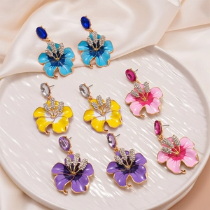 Orecchini vintage a fiori con smalto e cristalli su un vassoio di ceramica bianca