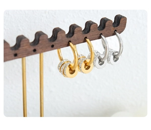 Details von gold- und silberfarbenen Creolen mit Zirkonia auf einem Holzständer