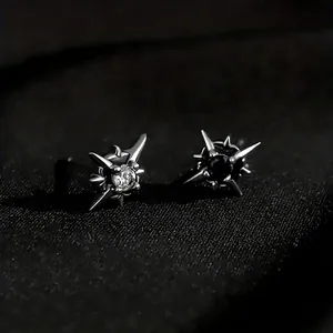 Gothic thorn star earrings with black and white zircon stones on dark fabric