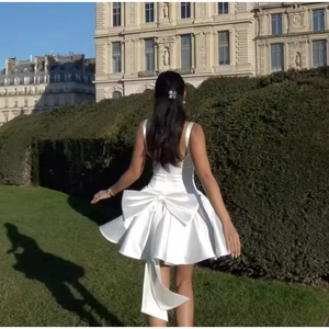 Détail d'une élégante robe mini en satin blanc avec un grand nœud au dos et fines bretelles