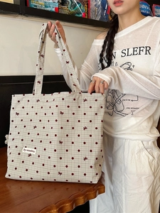 Grand sac cabas en toile à carreaux beige avec pois rouges porté par un mannequin