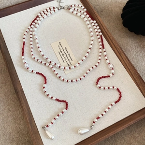 Detailed close-up of triple-layered pearl necklace with elegant water-drop pendants